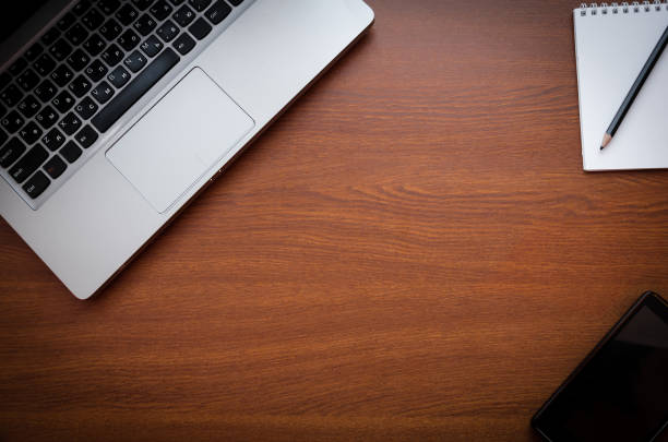istock Wood office desk table with laptop, glasses, notebook, pen, smartphone. Top view, copy space. 1034702488