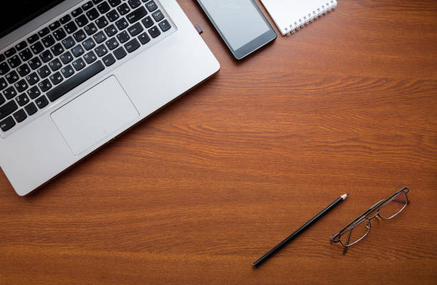 istock Wood office desk table with laptop, glasses, notebook, pen, smartphone. Top view, copy space. 1034702854