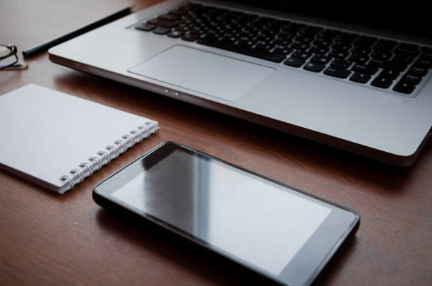 istock Wood office desk table with laptop, glasses, notebook, pen, smartphone. Top view, copy space. 1034702870