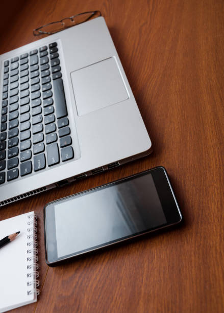 istock Wood office desk table with laptop, glasses, notebook, pen, smartphone. Top view, copy space. 1034702882