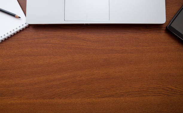Wood office desk table with laptop, glasses, notebook, pen, smartphone. Top view, copy space wooden table background.
