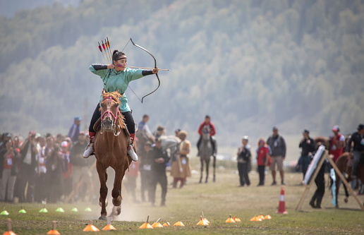 Lake Issyk-Kul, Kyrgyzstan, September 6th 2018: Woman shooting an arrow while riding a horse during World Nomad Games in Kyrgyzstan
