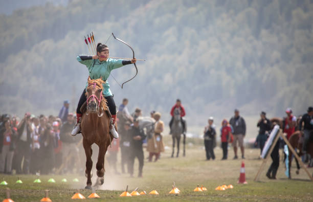 lady shooting an arrow while riding a horse at World Nomad Games stock photo
