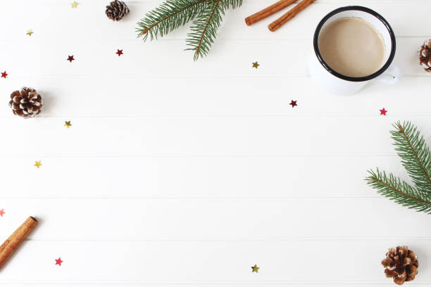 istock Christmas composition. Frame made of fir, spruce branches, pine cones, cinnamon sticks and glittering confetti stars on white wooden table background. Coffee in enamel mug. Flat lay, top view. 1034724814