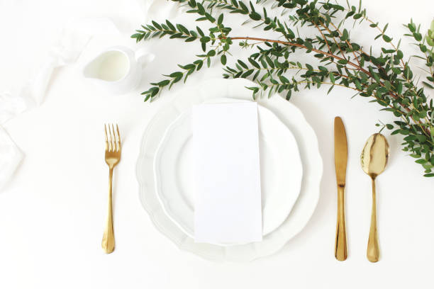 Festive wedding, birthday table setting with golden cutlery, eucalyptus parvifolia branch, porcelain plate, milk and silk ribbon. Blank card mockup. Rustic restaurant menu concept. Flat lay, top view Festive wedding, birthday table setting with golden cutlery, eucalyptus parvifolia branch, porcelain plate, milk and silk ribbon. Blank card mockup. Rustic restaurant menu concept, flat lay, top view restaurant table layout stock pictures, royalty-free photos & images