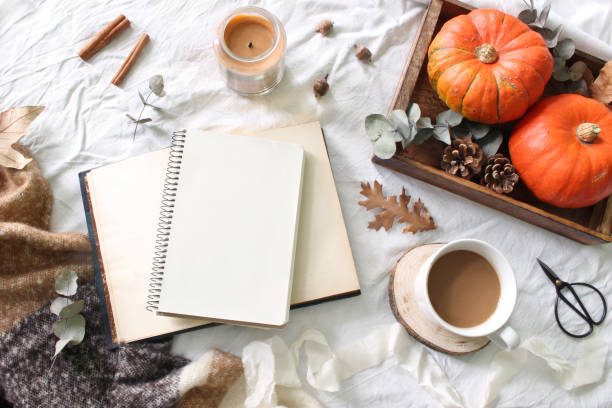 istock Autumn breakfast in bed composition. Blank notepad, book mockup. Coffee, candle,eucalyptus leaves and pumpkins on wooden tray. White linen bed sheet background. Thanksgiving, halloween. Flat lay, top. 1034724824