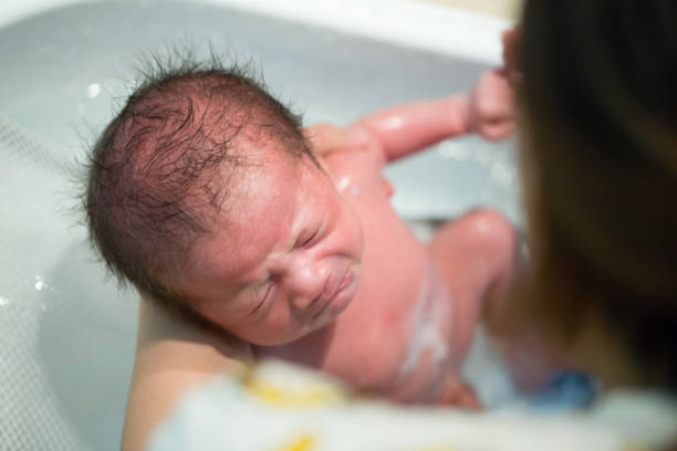 istock Mother bathing baby boy in white bathroom, Two week old 1034742780