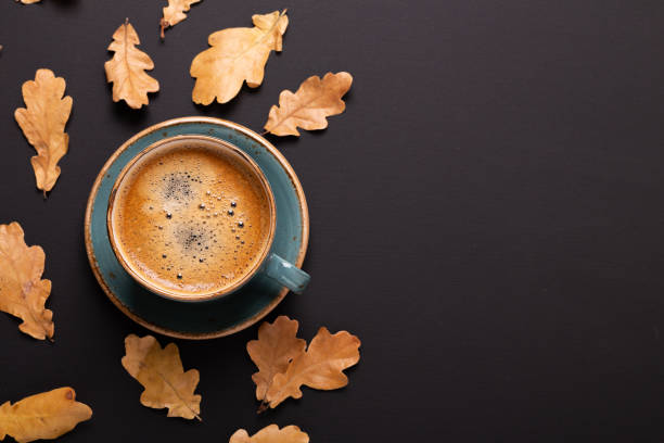 Autumn composition. Cup of coffee and dry leaves on black background. stock photo