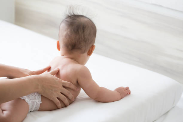 massage de bébé peut être relaxant et agréable - dos humain photos et images de collection