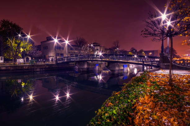 City by night with a bridge crossing a river and street lights in the autumn stock photo