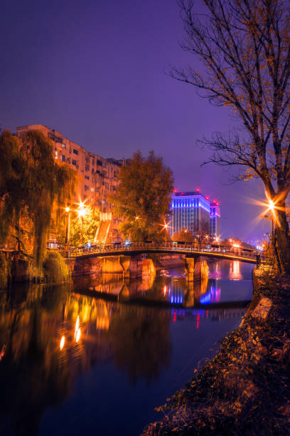 City by night with a bridge crossing a river with a modern building in the background stock photo