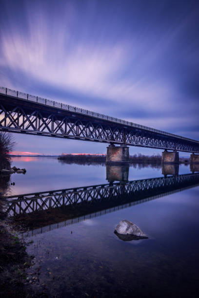 istock Long exposure clouds with a bridge crossing a big river 1034754012