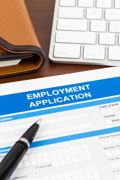 istock Employment application form with pen and keyboard; document is mock-up 1034754106