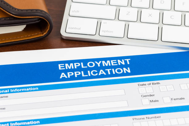 istock Employment application form with pen and keyboard; document is mock-up 1034754126