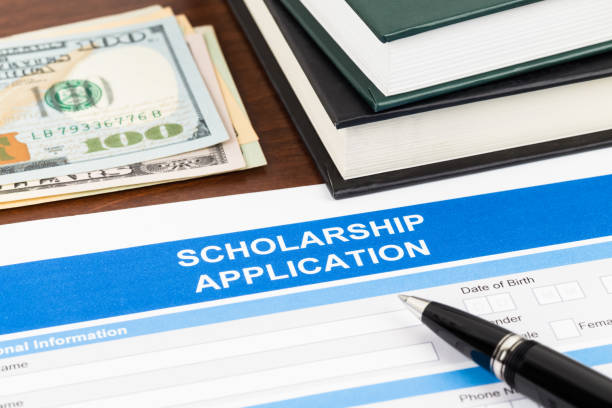 istock Scholarship application form with pen, dollar banknote and text book 1034754190