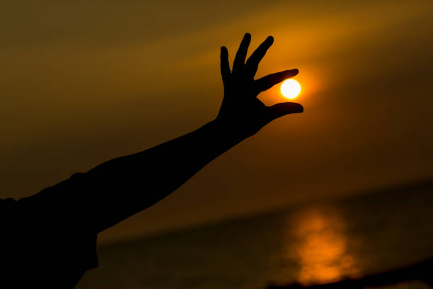 istock Silhouette and hand holding the sun. 1034761182