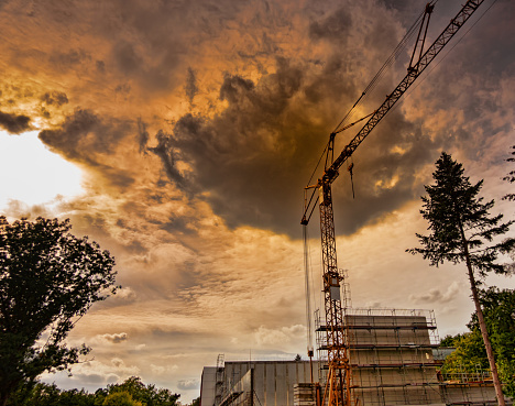 Abstract alienated photo of a construction site in the forest with a dark cloud above the crane