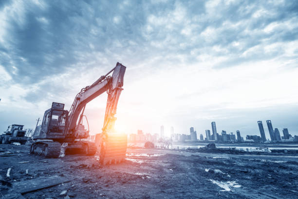 excavator in construction site on sunset sky background excavator in construction site on sunset sky background Earthmoving stock pictures, royalty-free photos & images