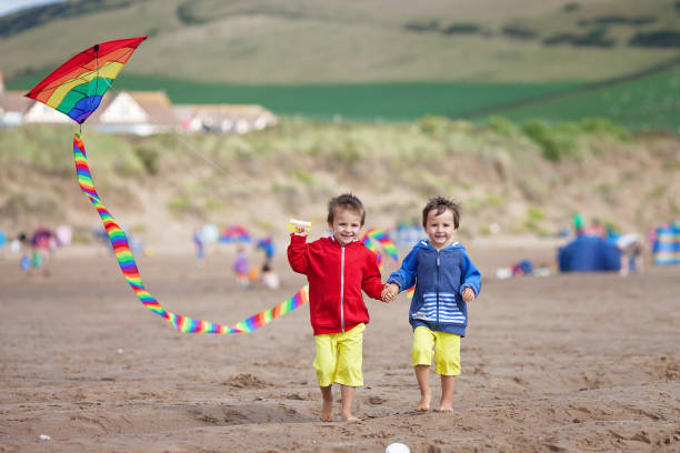 Two children playing with a kite on the beach, summertime