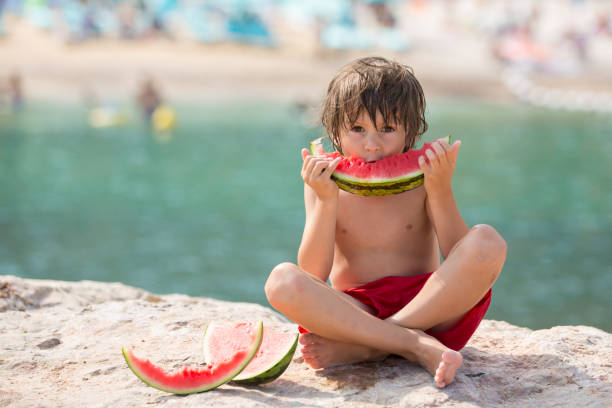 istock Cute little child, boy, eating watermelon on the beach 1034768280