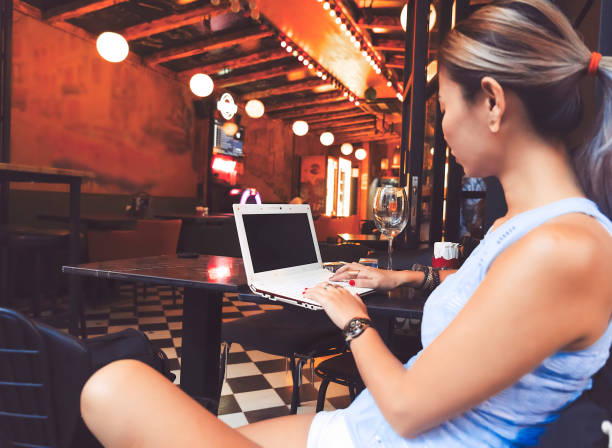 istock Woman working with laptop and drinking white wine in pub 1034768678