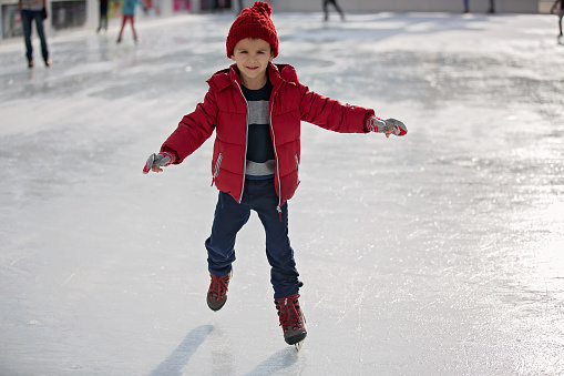 Happy boy with red hat and jacket, skating during the day, having fun