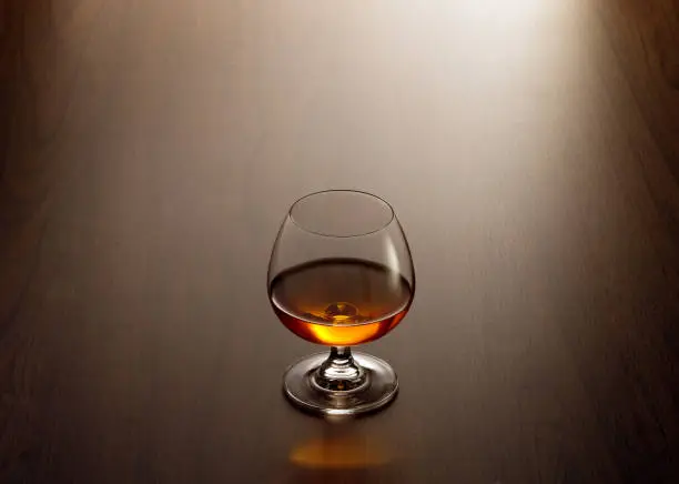 view of glass of  cognac on brown color wooden table surface