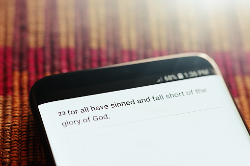 A quote from the Bible displayed on the screen of a smart phone: ...for all have sinned...
