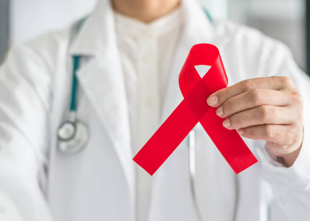 aids-rotes band in der hand des arztes für welt aids tag und hiv virus bewusstsein konzept - hiv stock-fotos und bilder