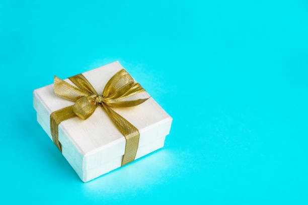 istock Gift or present box decorated with golden ribbon on blue background. Top view, copy space. Birthday, Mothers day, Wedding, Valentine Day concept. 1034799056