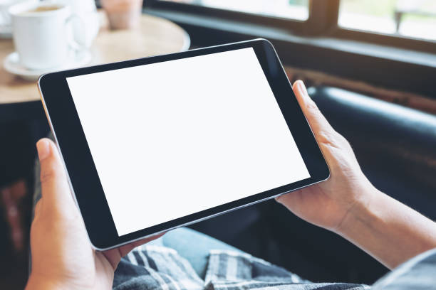 istock Mockup image of hands holding black tablet pc with blank white desktop screen while sitting in cafe 1034803086