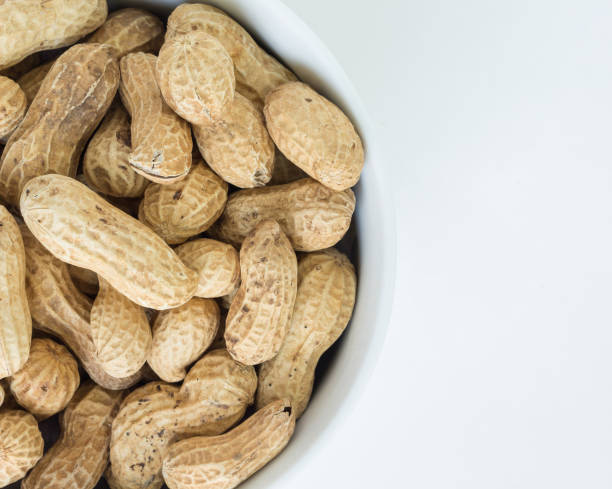 istock peanut pile in white bowl top view on white background 1034810876