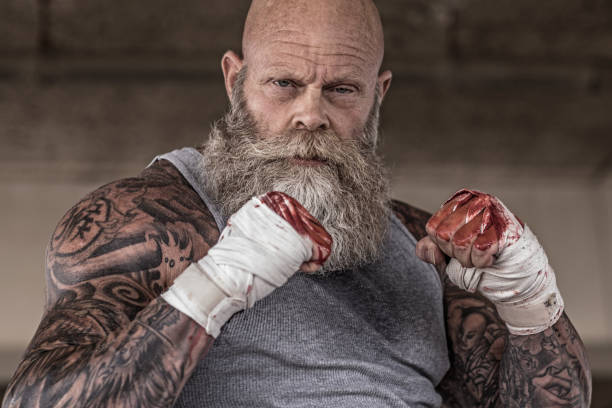 Tattooed Senior Man During fight Workout Bearded Aggressive Redhead Senior Man during mma fight outdoor workout on the beach old man boxing stock pictures, royalty-free photos & images