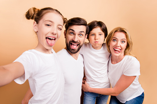 Self portrait of young attractive adorable beautiful smiling family, bearded father, blonde mother and their little children, boy and girl, wearing white T-shirts, showing their tongues