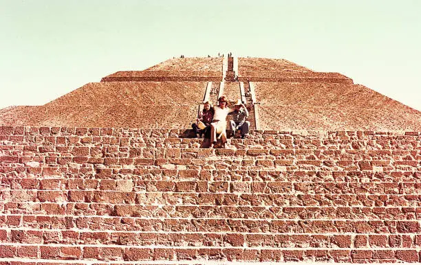 Vintage image of a mother and her children saluting from the middle of the Sun pyramid in teotihuacan, in Mexico.