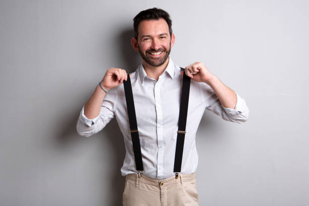 Portrait of trendy man with beard holding suspenders