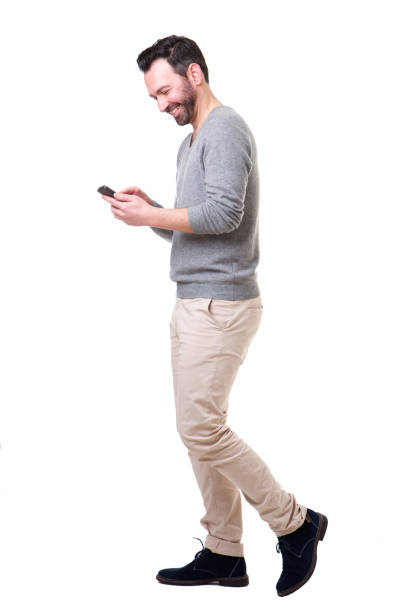 istock Full length side of man walking with mobile phone 1034837370