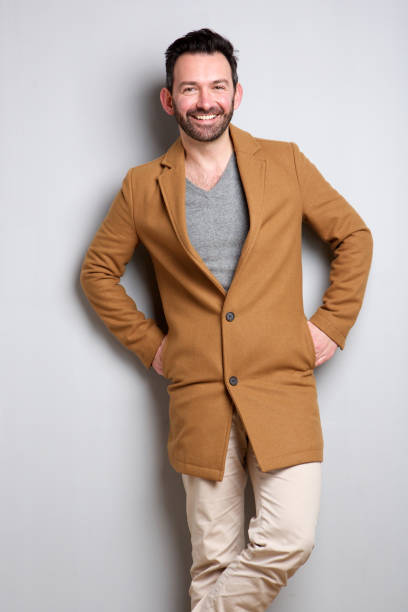 istock trendy man with coat posing against gray background 1034837372