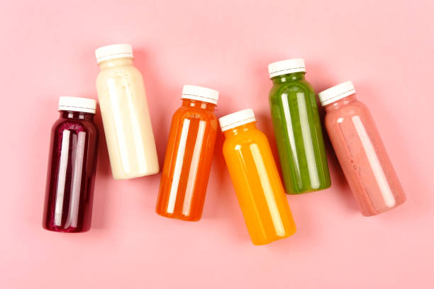 Bottles of multicolored smoothies Bottles of multicolored smoothies or juices on pink background. Flat lay style. refreshment stock pictures, royalty-free photos & images