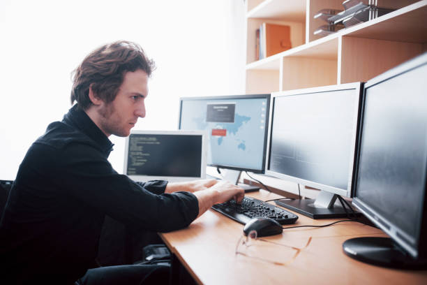 istock The young dangerous hacker breaks down government services by downloading sensitive data and activating viruses. A man uses a laptop computer with many monitors 1034843078