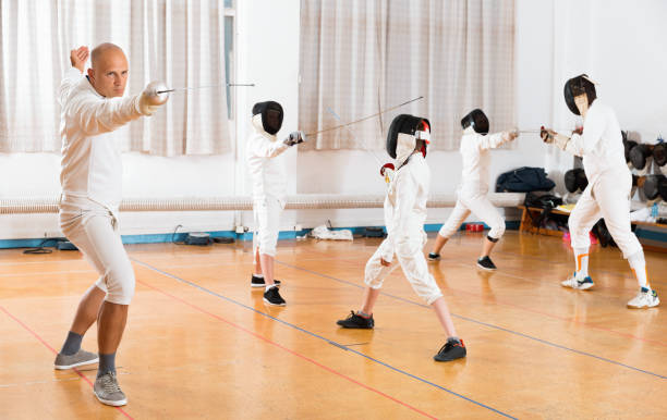 istock Coaches demonstrating to young athletes attack movements with rapier during fencing workout 1034845312