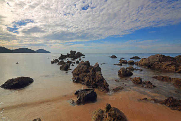 istock Seascape with sand stones coast and white clouds 1034849200