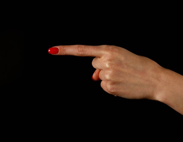 przycięta ręka kobiety wskazująca na czarnym tle - red nail polish zdjęcia i obrazy z banku zdjęć