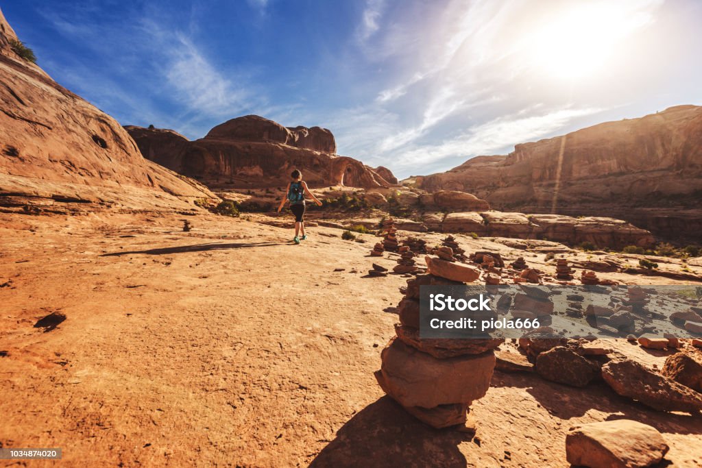 Woman solo hiking in the Colorado plateau: Corona arch Rock Cairn Stock Photo