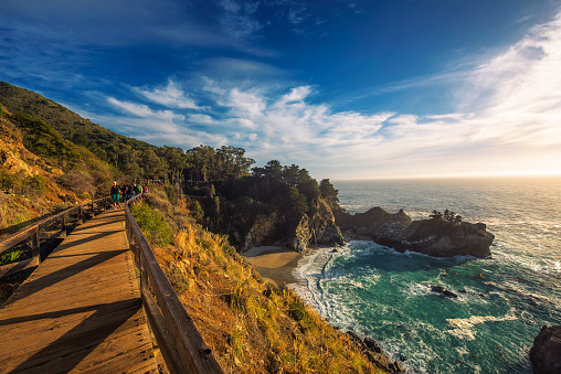 Big Sur, California, USA - January 7, 2018 : Group of tourists coming to the McWay Falls in Big Sur state park, California.