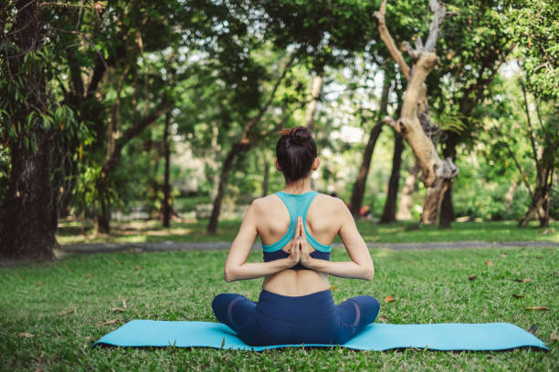 kobieta robi joga stanowią / medytacji na zewnątrz zielony park / ogród z szczęśliwym uczuciem w godzinach porannych - yoga class caucasian young adult group of people zdjęcia i obrazy z banku zdjęć