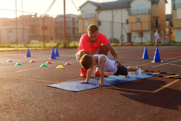 istock Determinative young football coach learning little boy how to do push ups. Early summer morning training. 1034893336
