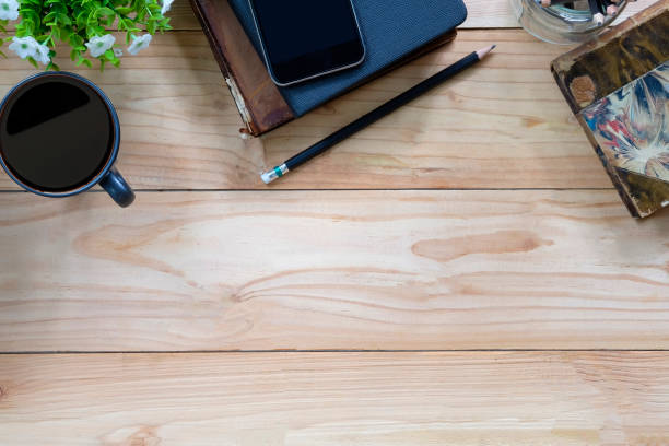 istock Office desk a coffee, book, pencil and smartphone on copy space workspace table top view with wood texture. 1034920312