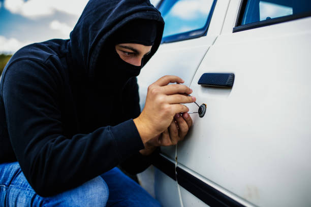 istock Masked man is trying to get into an old car 1034926674