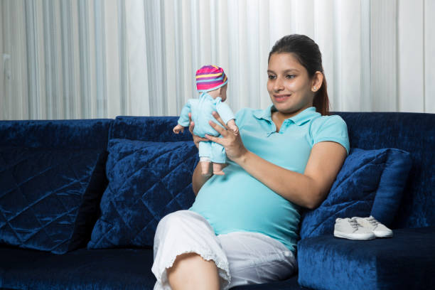 donna incinta che tiene orsacchiotto - immagine di repertorio - baby shower women home interior indoors foto e immagini stock